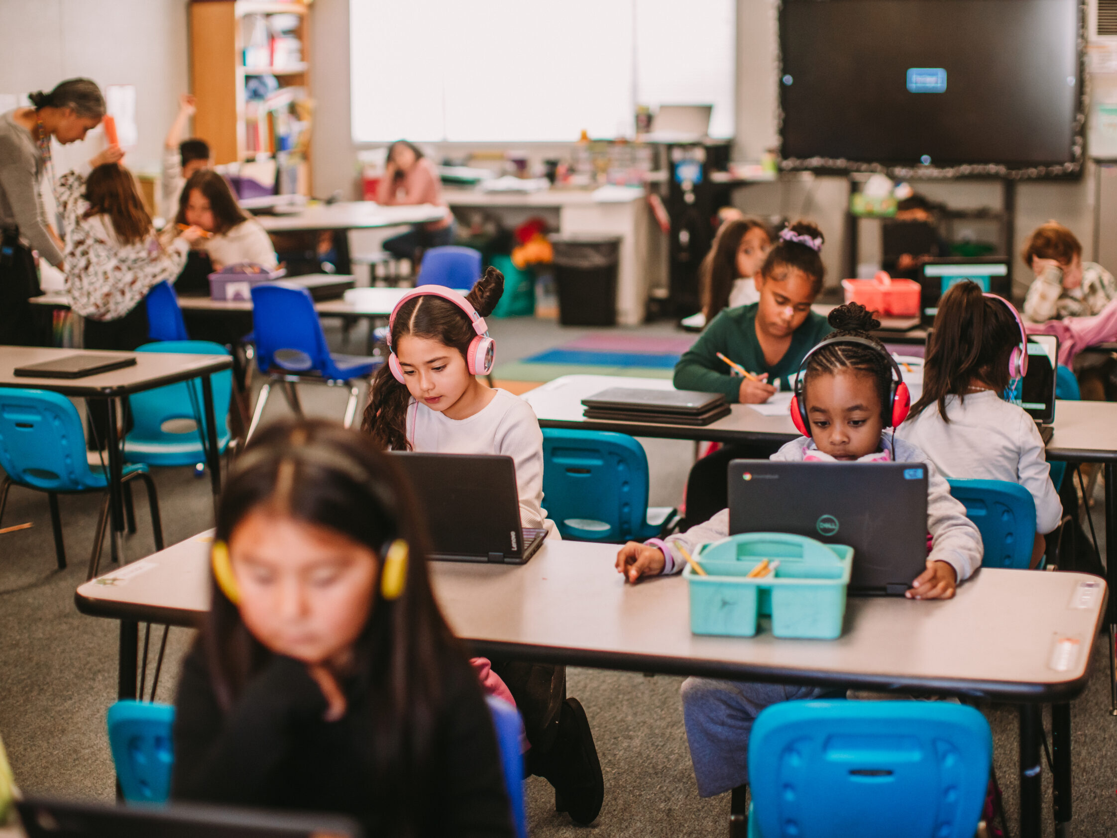 Third grade students actively engaged in learning on their Chromebooks while wearing headphones.