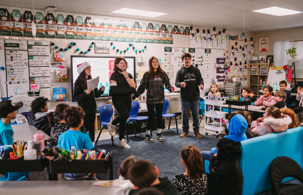 Four sixth graders perform a PBL skit in front of a class of first grade students.